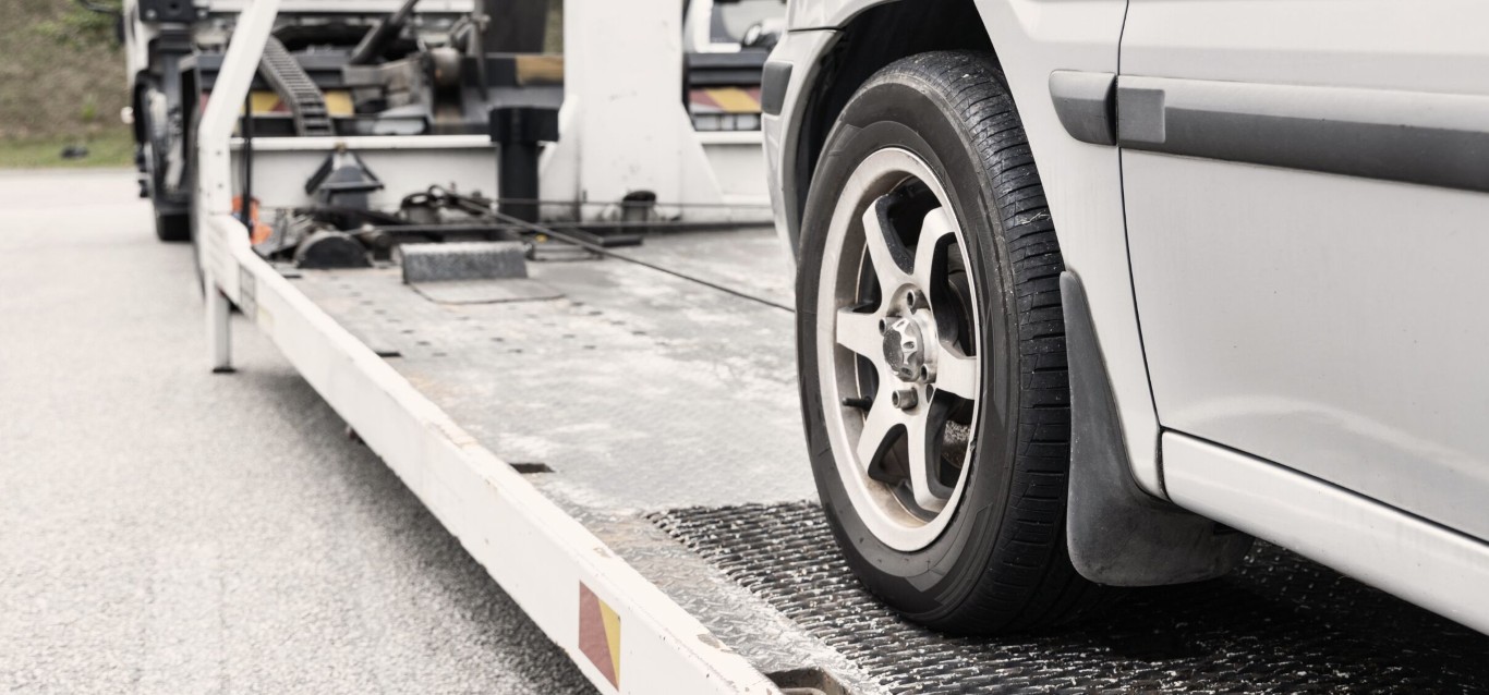 Car being loaded onto a flatbed tow truck ramp for winch out service near Solana Beach, CA